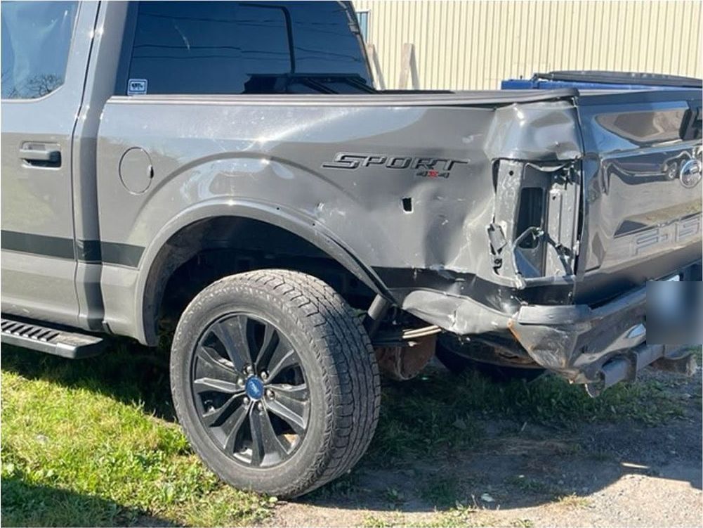 Grey Ford F-150 with crushed rear bedside and missing tail light