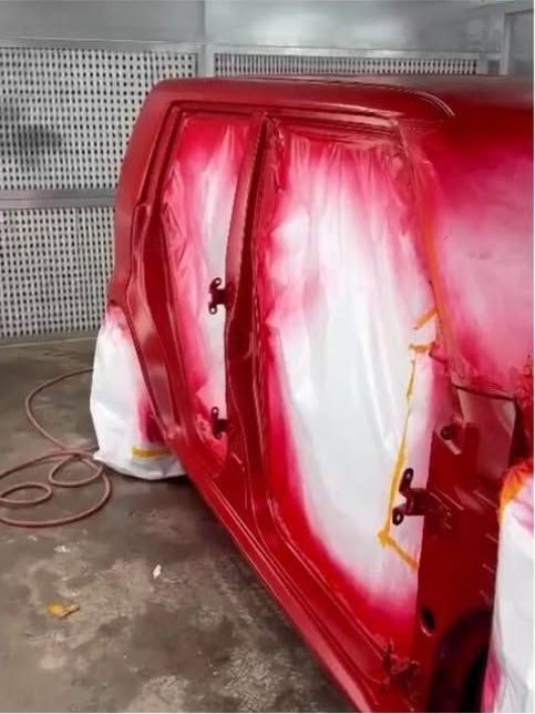 Scion xB panels masked and freshly painted red inside the paint booth
